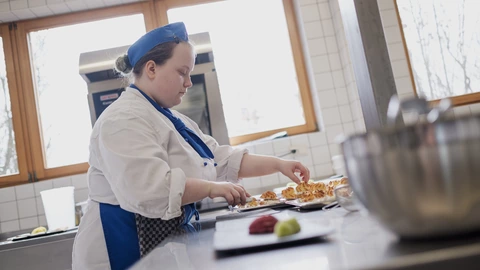 Eine Auszubildende bereitet Essen in der Küche vor.