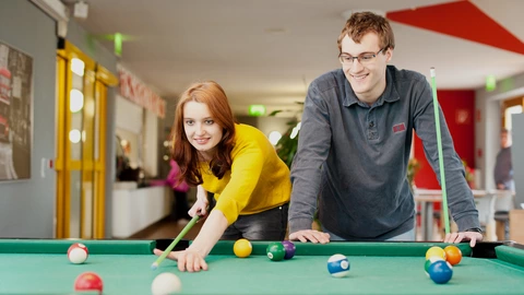 Zwei Auszubildende spielen Billard.