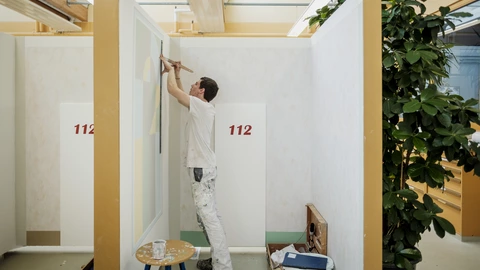 Ein Auszubildender arbeitet an einem Wandbild.