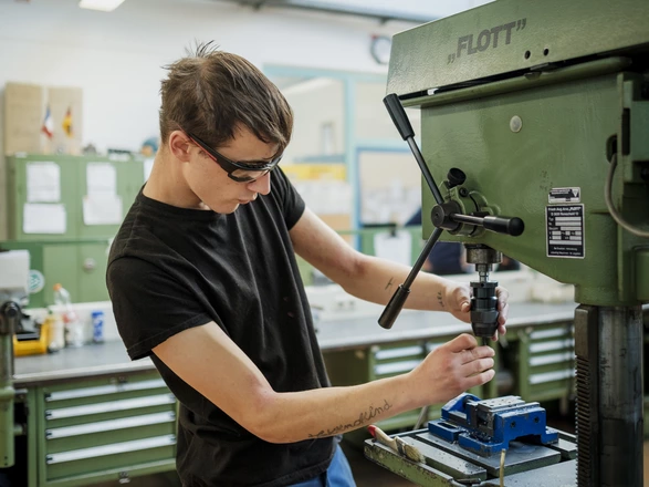 Ein Auszubildender arbeitet an einer Maschine im Metallbereich.