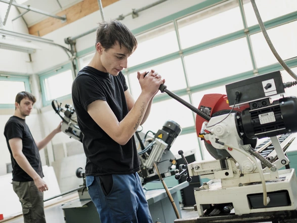 Zwei Auszubildende arbeiten an Maschinen im Metallbereich.