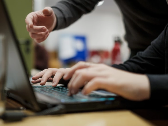 Nahaufnahme von einem Laptop und mehreren Händen.