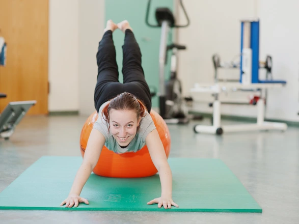 Eine Jugendliche turnt auf einem Gymnastikball.