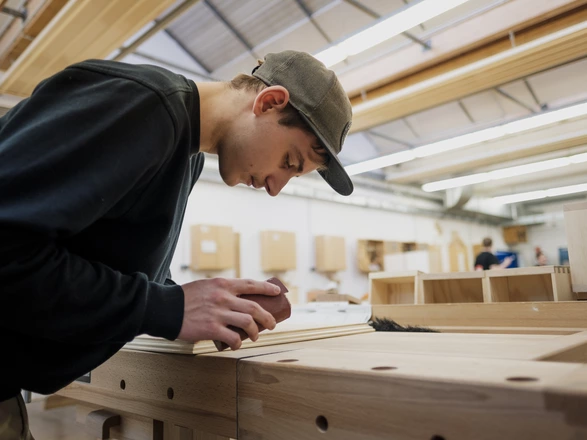 Ein Auszubildender arbeitet mit Holz.