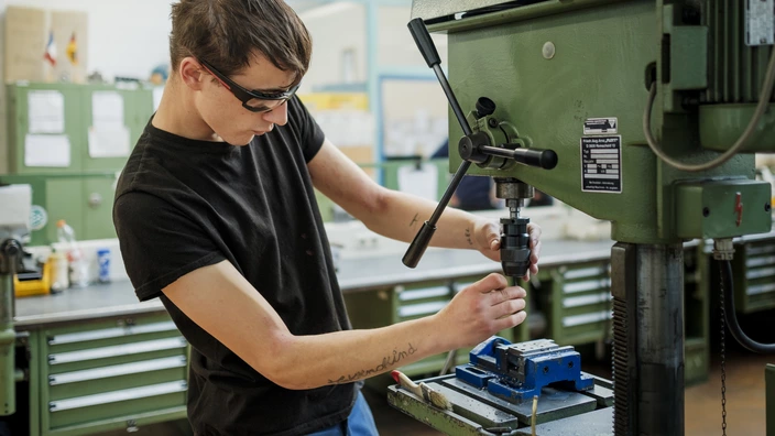 Ein Auszubildender arbeitet an einer Maschine im Metallbereich.