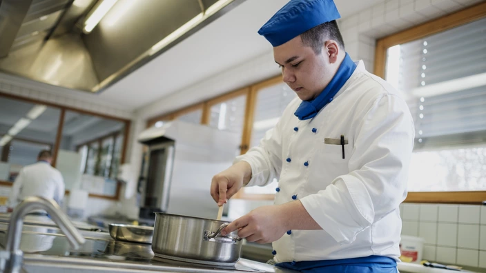 Ein Auszubildender im Bereich Küche bei der Zubereitung eines Gerichts