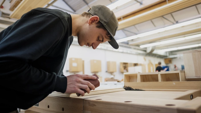 Ein Auszubildender arbeitet mit Holz.